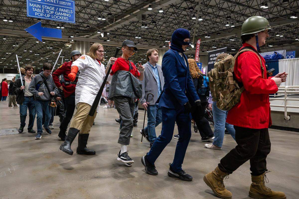 Visitors in cosplay join in a conga line during Planet Comicon at the Kansas City Convention Center on Friday, March 21, 2025.