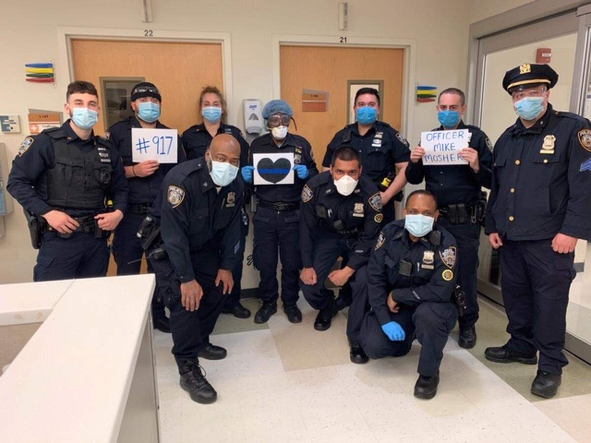 At Stacie Kelly's urging, 10 New York City police officers paid tribute in the hall of the hospital to slain Overland Park police officer Michael Mosher.