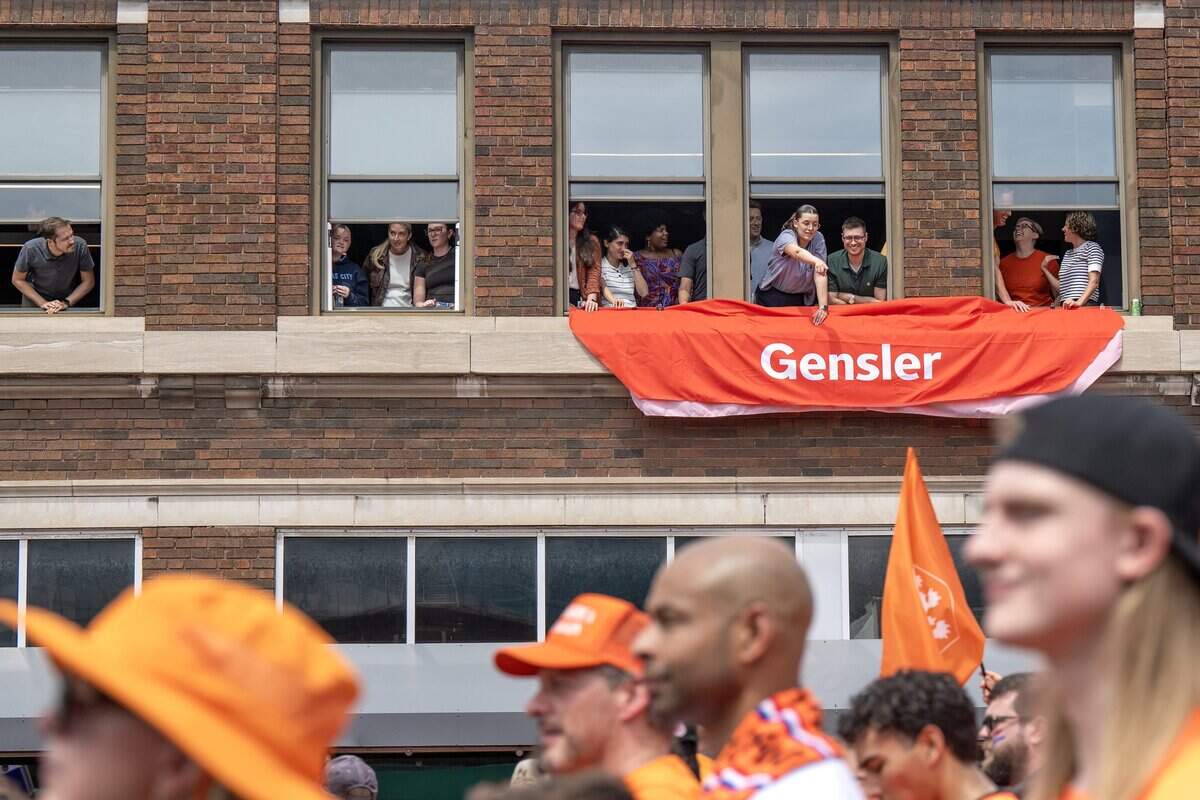 Fans watch from a rooftop overlooking Grand Boulevard as participants take part in the Orange Walk on Thursday, June 25, 2026, in Kansas City.