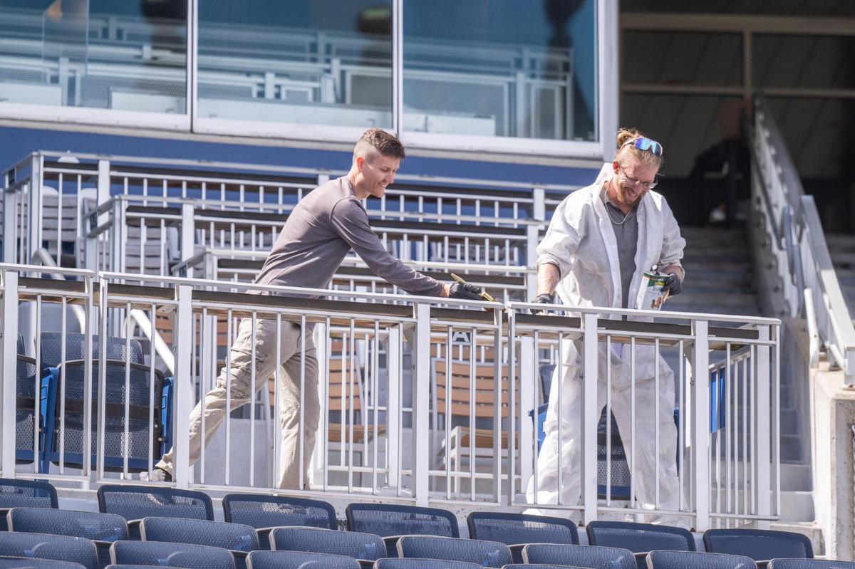 Painters paint lacquer on wood bar tops at Kauffman Stadium on Tuesday, March 25, 2025. After sitting mostly vacant all winter, crews worked throughout the day to prepare for Opening Day for the Kansas City Royals.