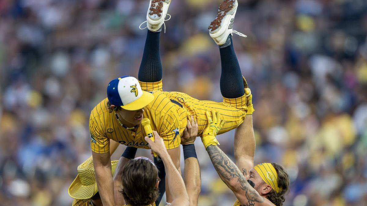 Savannah Bananas player (24) is held up by his teammates while singing during a Banana Ball game against the Indianapolis Clowns at Kauffman Stadium Saturday, May 30, 2026, in Kansas City.