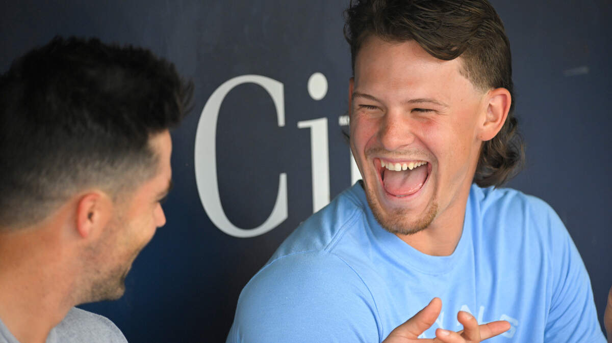 Kansas City Royals’ Bobby Witt Jr., right, and Whit Merrifield, left, share a laugh in the dugout before their baseball game against the Oakland Athletics, Friday, June 24, 2022, in Kansas City, Mo. (AP Photo/Reed Hoffmann)