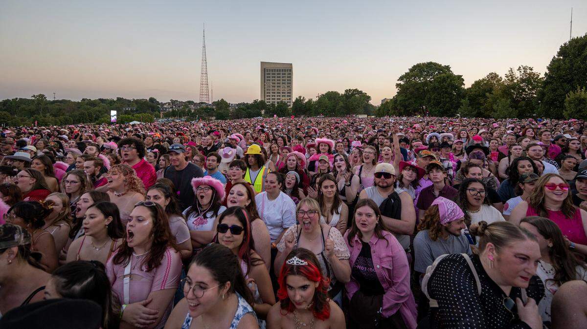 Fans, many dressed in pink, fill the lawn of the National WWI Museum and Memorial as they await Chappell Roan performance during her Visions of Damsels and Other Dangerous Things tour stop on Friday, Oct. 3, 2025, in Kansas City.
