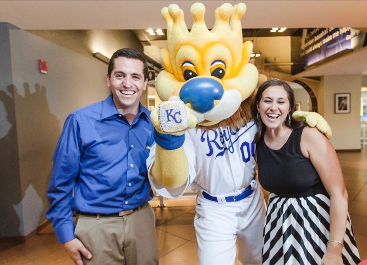 Jorge Guevara and his wife, Megan, during their rehearsal dinner at Kauffman Stadium. They were joined by Sluggerrr, mascot of the Kansas City Royals.