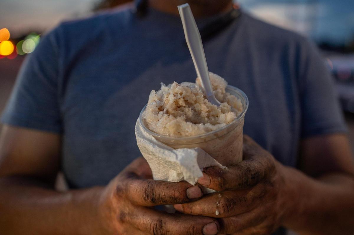 Saul Franco shows off a nuez-flavored raspado bought from the “water stand” under a tent in a parking lot off 18th Street and Central Avenue.