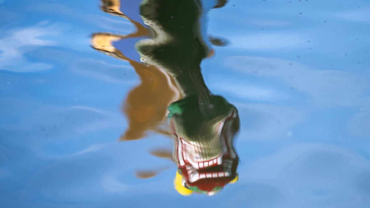 A dragon boat is reflected in the water during the KC Dragon Boat Festival on Saturday, Sept. 28, 2024, at Shawnee Mission Park.