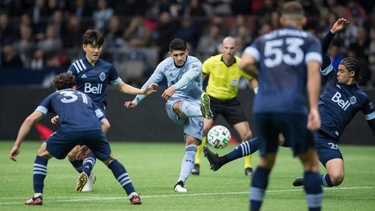 Sporting Kansas City’s Alan Pulido takes a shot on goal past Vancouver’s Jasser Khmiri, back right, as Inbeom Hwang, back left looks on Saturday in Vancouver, B.C.