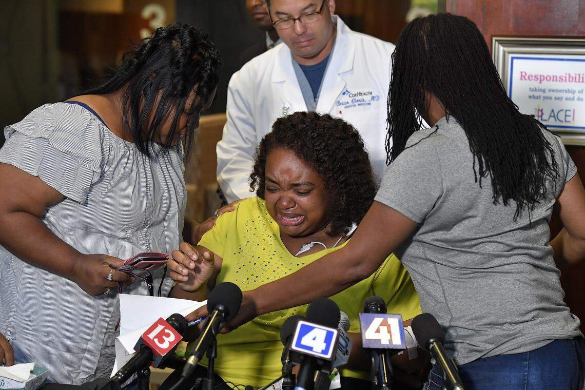 Duck boat survivor Tia Coleman is comforted by family after answering questions on Saturday, July 21, about her escape from the sinking boat and the loss of nine family members on Table Rock Lake, in Branson, Mo.