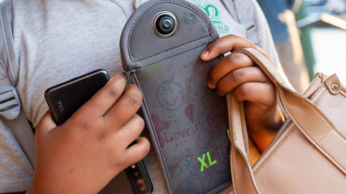 An Kentucky high school student shows their Yondr pouch before locking their phone away in the pouch as they arrive for school.