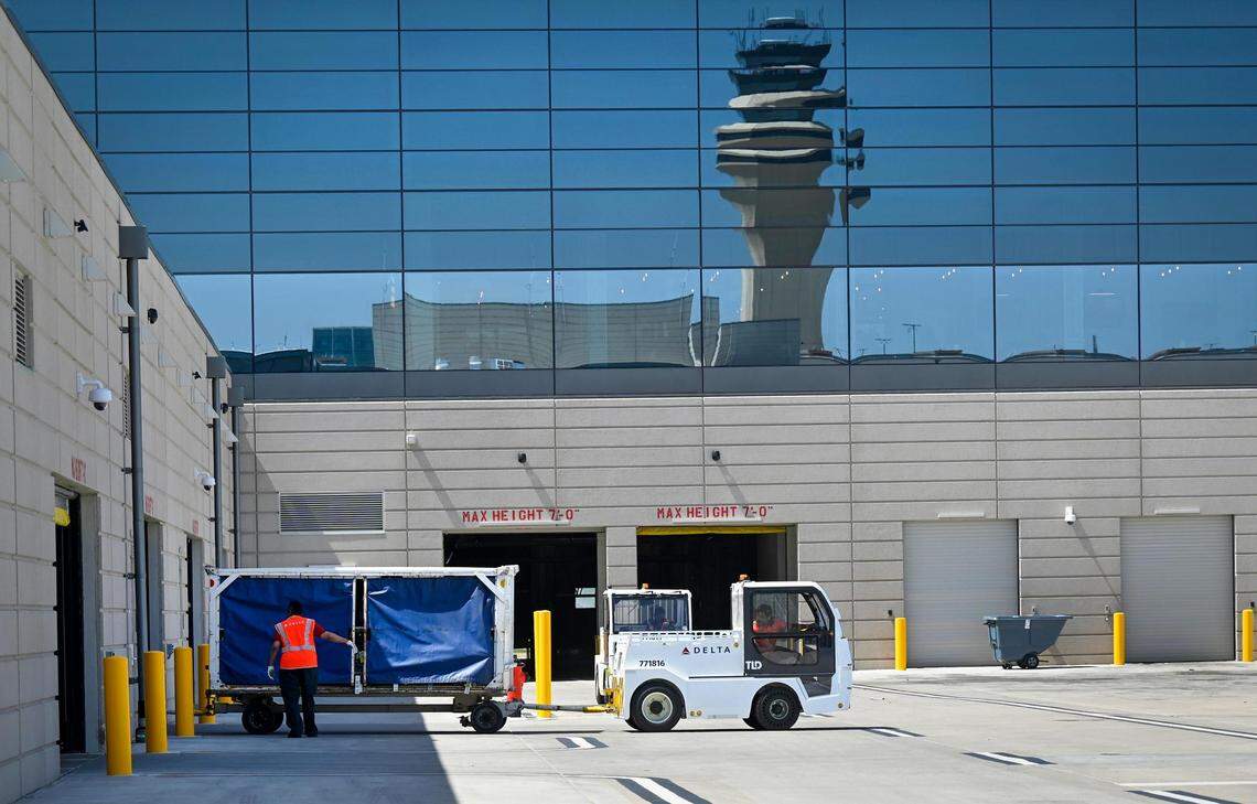The air traffic control tower is reflected in the terminal as a tug truck moves a baggage cart in April 2023 at Kansas City International Airport.