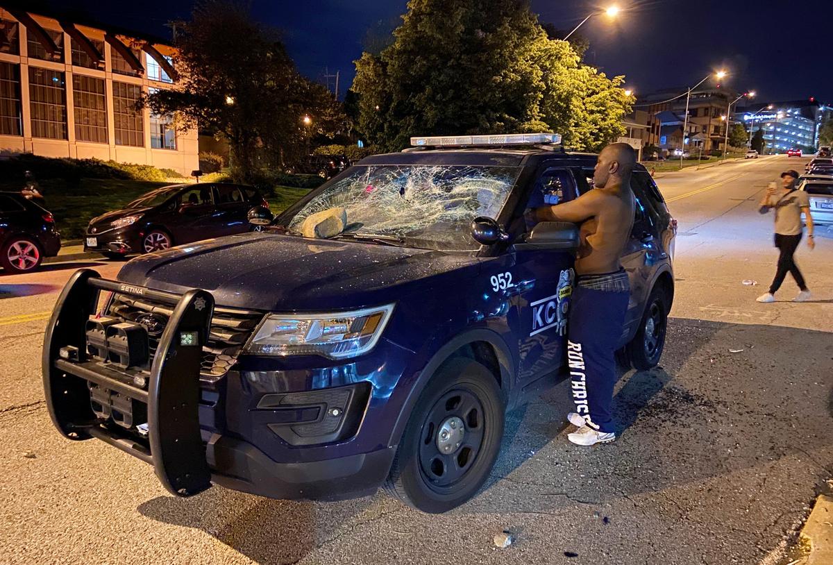 A protester puts his hands inside Kansas City Police Department police car that later caught fire during protests Saturday night at the Country Club Plaza. A protest meant to bring awareness to the death of George Floyd while in custody of Minneapolis police turned violent when stores and the police car became targets.