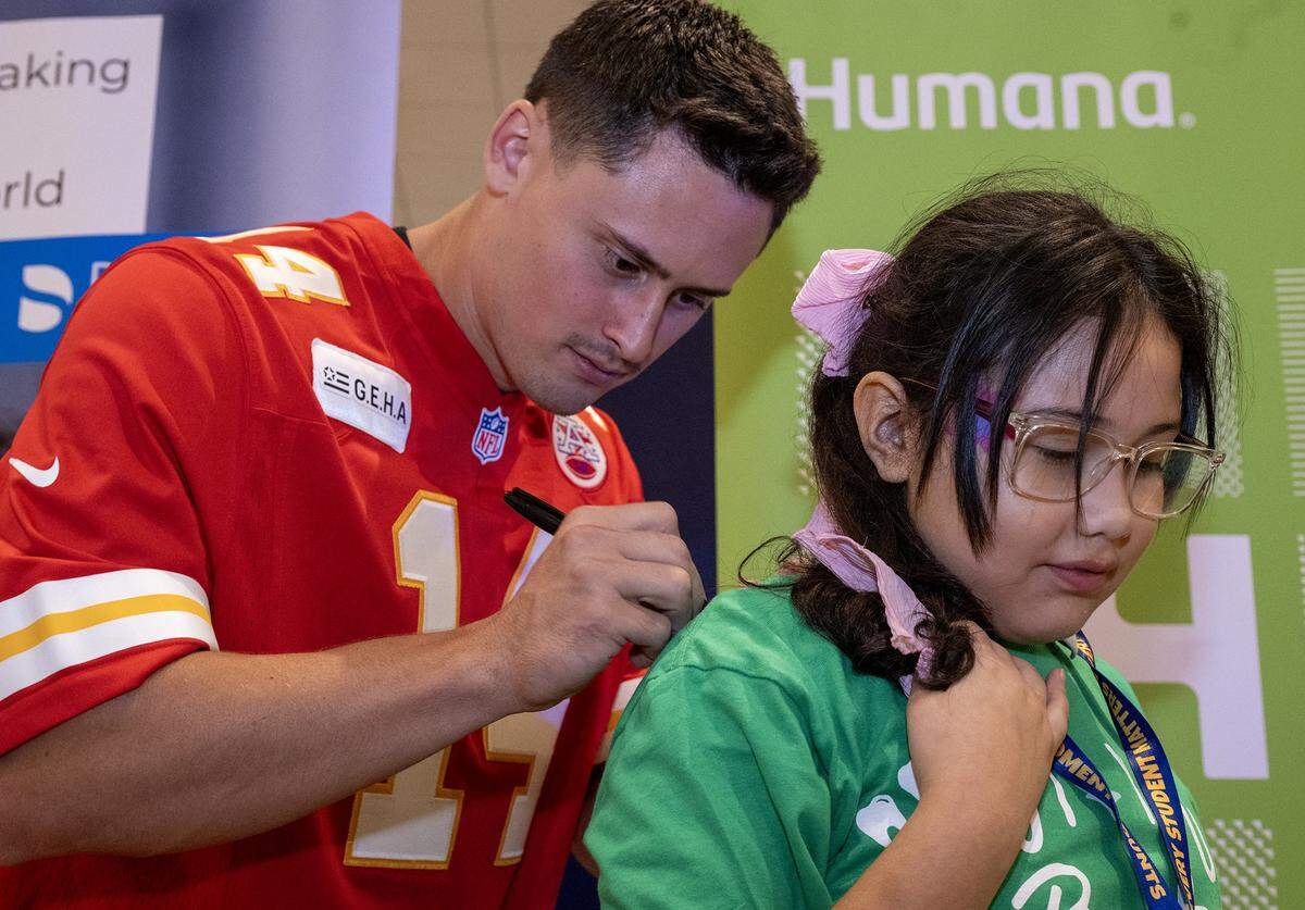 Kansas City Chiefs punter Matt Araiza signs an autograph for Angie Ramirez-Maese, 9, a student at Our Lady of Unity Catholic School in Kansas City, Kansas, during the TeamSmile dental tailgate on Tuesday, Sept. 9, 2025 at GEHA Field at Arrowhead Stadium. More than 200 volunteer dentists, hygienists, and dental assistants, backed by TeamSmile and the Chiefs, provided free dental care to 300 children from Kansas City, Missouri, and Kansas City, Kansas schools.