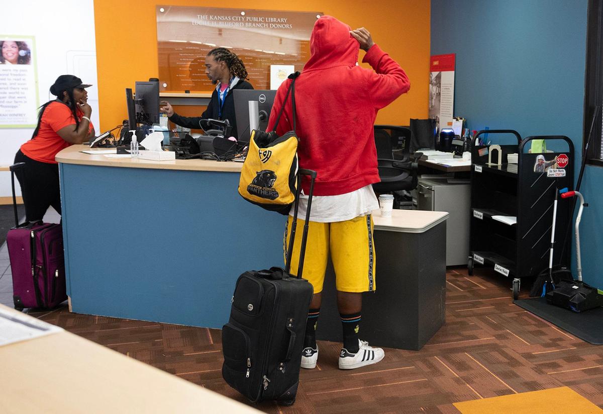 Bobby Layton, center, a senior library technical assistant, helps a library patron at the customer service desk at the Lucile H. Bluford Branch of the Kansas City Public Library on Wednesday, Sept. 18, 2024. Layton, a 23-year veteran library employee, said he really enjoys helping the customers of the library.