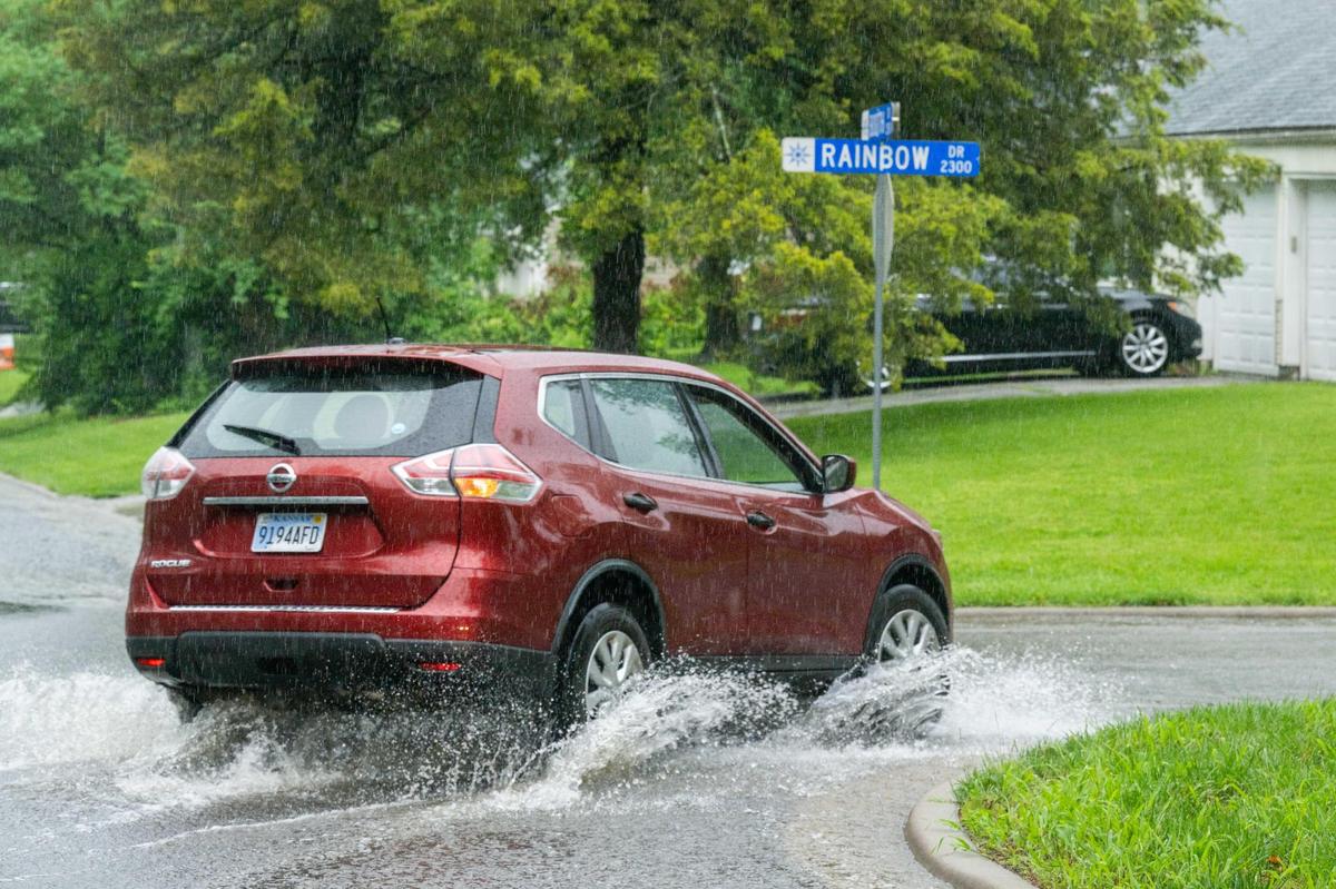 Cars drive through flooded residential streets in Prairie Village on Tuesday, June 3, 2025. A flash flood warning is in effect.