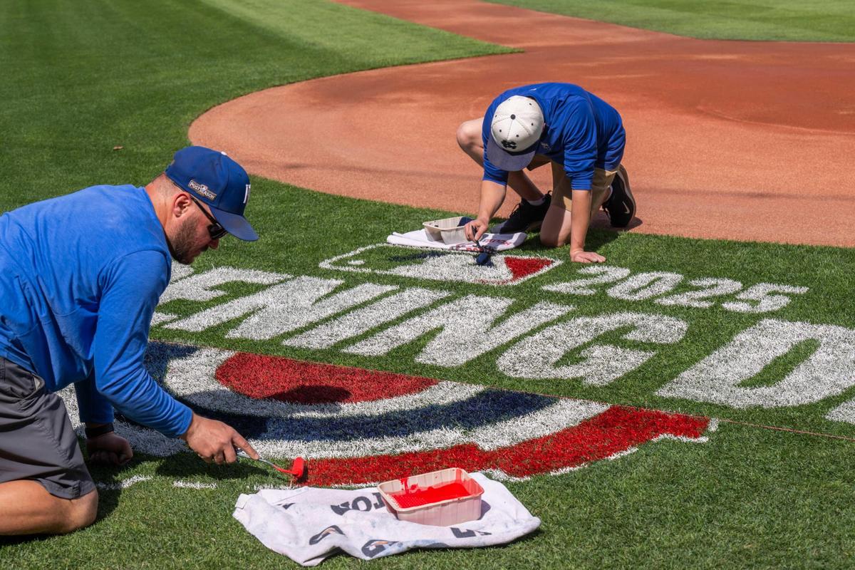 A team of Royals grounds crew workers block in red and blue paint for the MLB Opening Day logo on the field at Kauffman Stadium on Tuesday, March 25, 2025. The task is mandated by Major League Baseball for all fields to feature the logo.