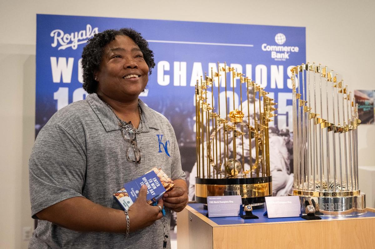 Lisa Roby takes a photo next to the 1985 and 2015 World Series trophies and World Series rings at the Royals’ Crowning Achievements Exhibit at Commerce Bank in downtown Kansas City on Tuesday, March 18, 2025. Several items from the Royals’ Hall of Fame are featured at the exhibit including the trophies, rings, and player memorabilia.