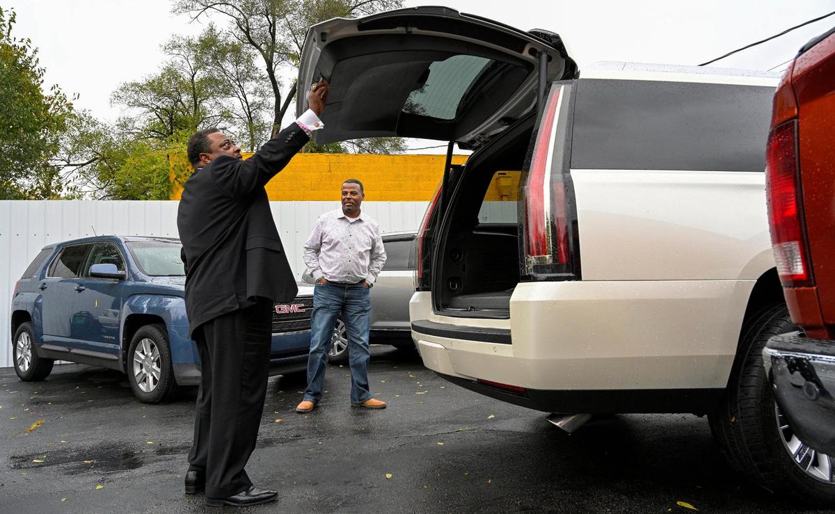 As the Rev. Clifford Jackson checks out a Cadillac Escalade, Marcus Watson describes its features. Jackson is a repeat customer at Watson’s Auto Wholesale, 6740 Prospect Ave.
