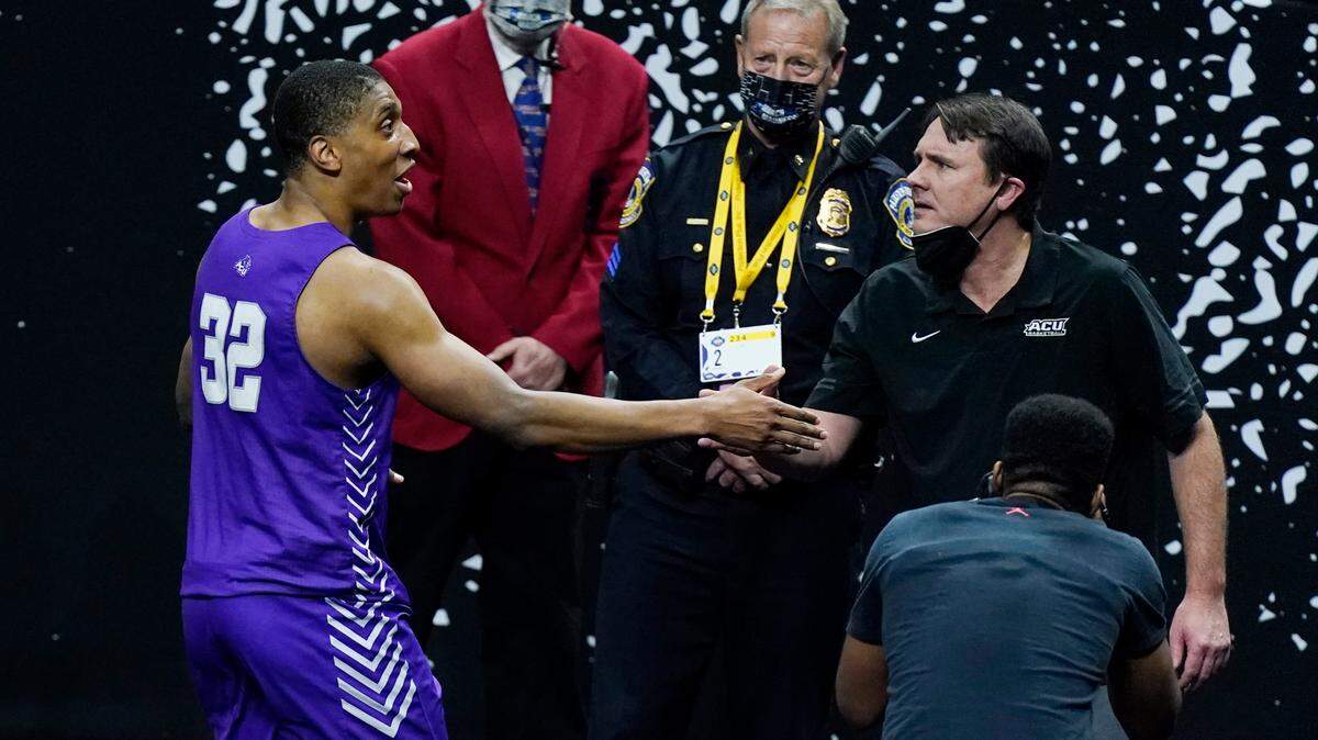 Former Abilene Christian head coach Joe Golding, now head coach at UTEP, shakes hands with Joe Pleasant (32) as they leave the court after Abilene Christian upset Texas in a college basketball game in the first round of the NCAA tournament at Lucas Oil Stadium in Indianapolis Sunday, March 21, 2021. Pleasant made two decisive free throws as Abilene Christian beat Texas 53-52. (AP Photo/Mark Humphrey)