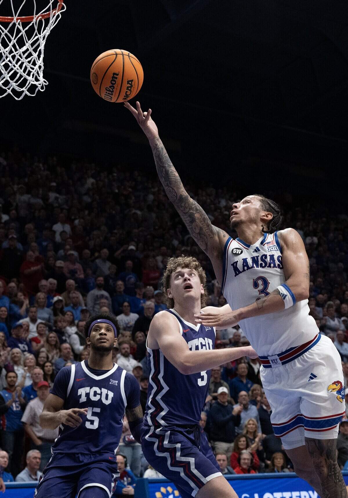 Kansas Jayhawks guard Tre White (3) goes for two in front of TCU Horned Frogs guard Liutauras Lelevicius (3) in the first half at Allen Fieldhouse in Lawrence on Tuesday, Jan. 6, 2025.