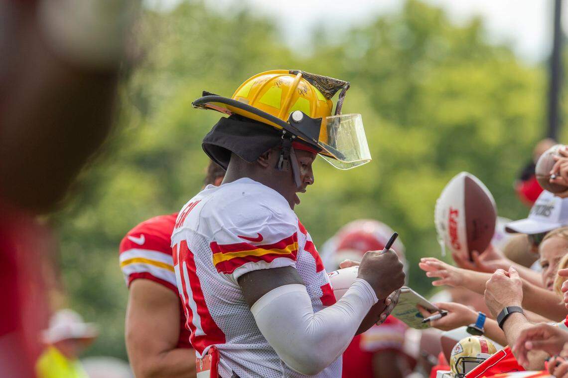 Kansas City Chiefs linebacker Willie Gay signs autographs while wearing a fan’s firefighter hat after practice at Chiefs training camp in St. Joseph in 2022.