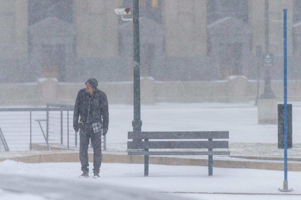 A man waits for a city bus as snow falls outside of Union Station on Thursday, Dec. 22, 2022, in Kansas City.