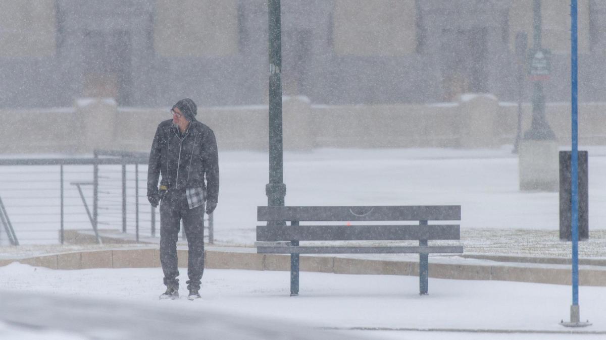 A man waits for a city bus as snow falls outside of Union Station on Thursday, Dec. 22, 2022, in Kansas City.
