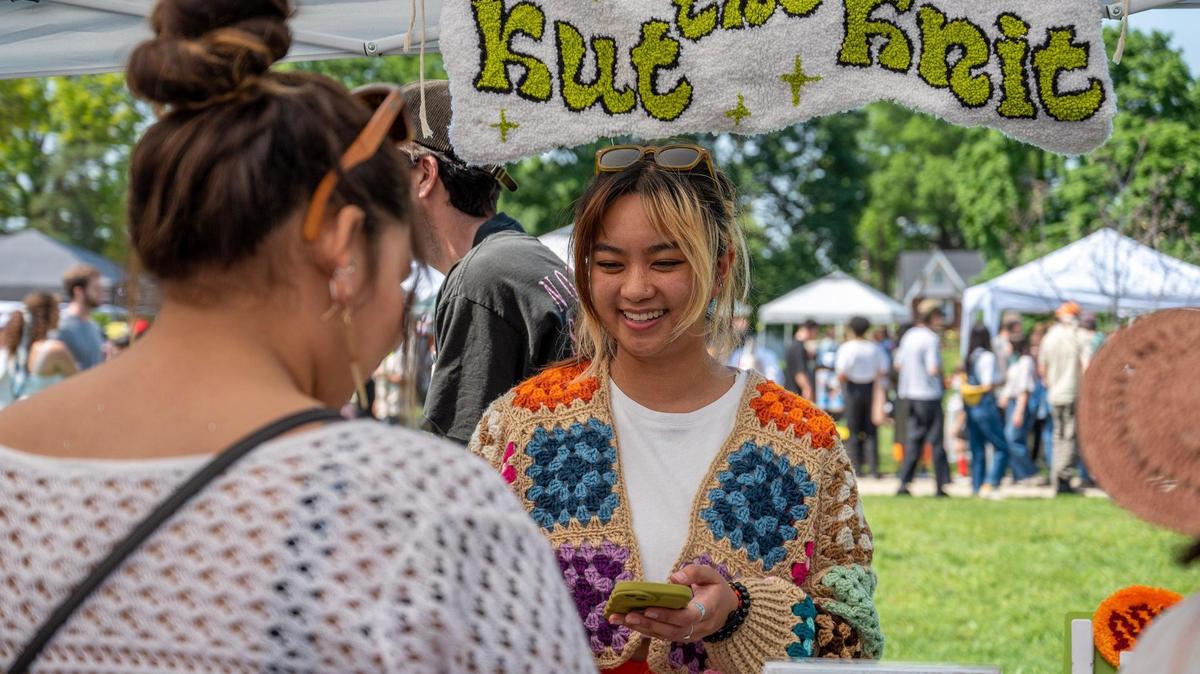 Kathryn Cacho helps a customer purchase an item at the Kut the Knit booth during the AAPIconic Festival on Saturday, May 20 in Kansas City. Cacho made the cap that Taylor Swift wore to the Chiefs-Patriots game on Sunday, Dec. 17. 