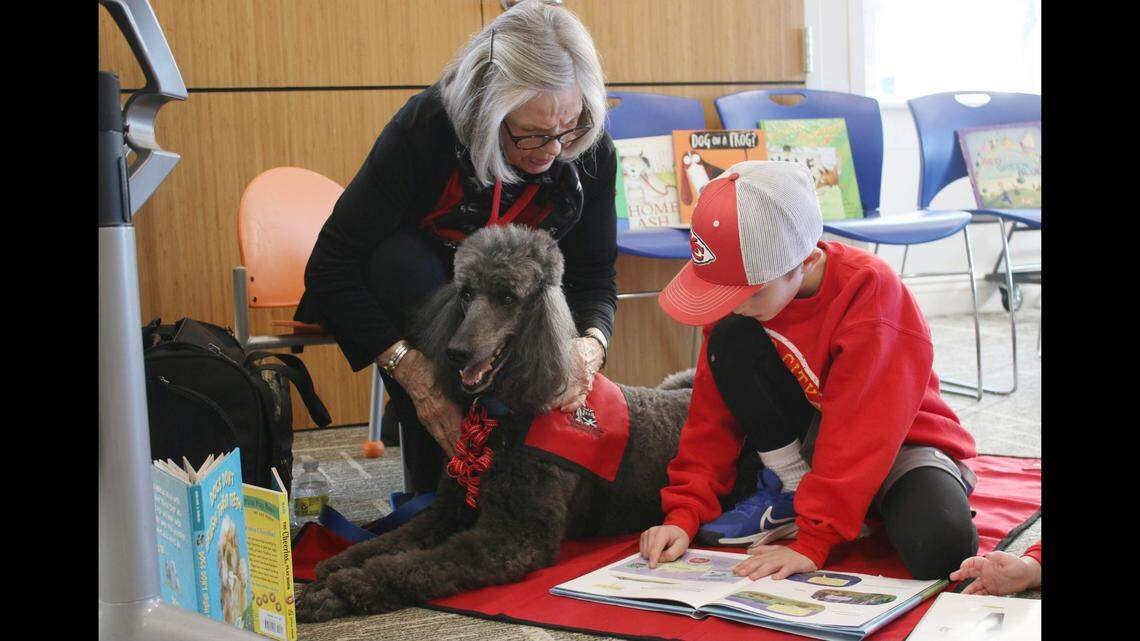 Volunteer Fran Lancaster and her poodle Otto Francis listen as Leawood resident Wes Monahan, 7, reads them a story.
