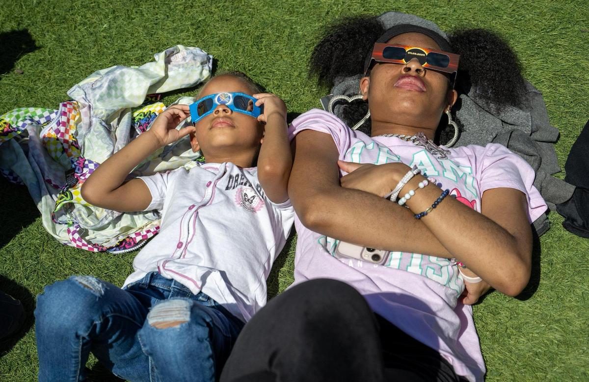 Loyalty Washington, 3, and Zakhiyah Estis, 20, of Kansas City, Kansas, joined spectators at the solar eclipse watch party at Legends Outlets.