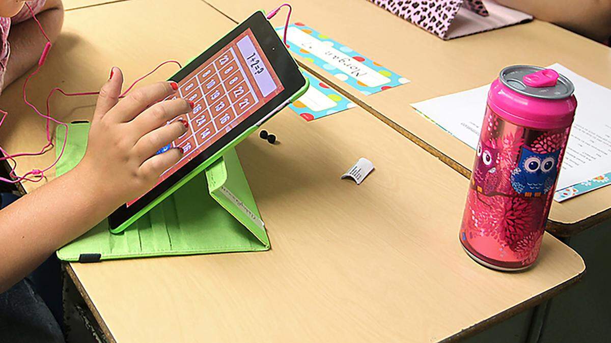 An elementary school student uses an iPad for a lesson.