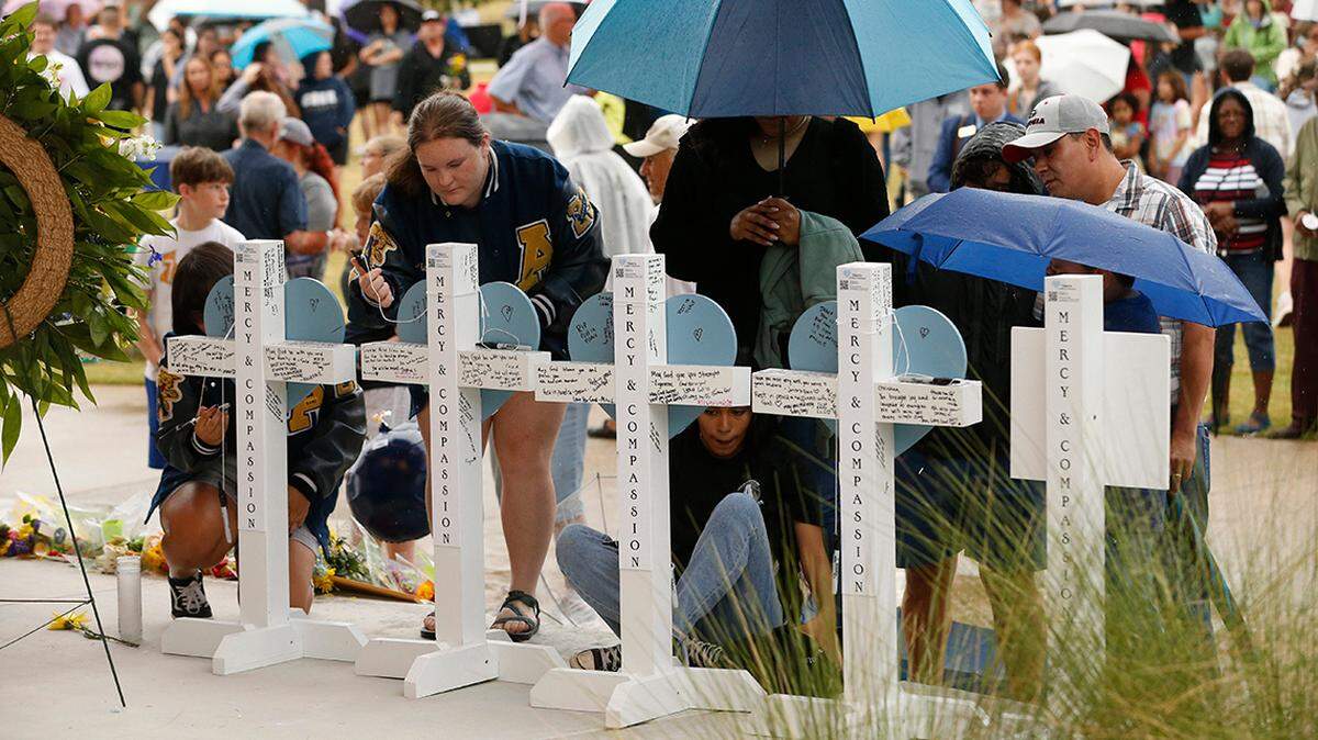 Attendees sign memorial crosses during a vigil for the lives lost in a mass shooting this month at Apalachee High School in Winder, Georgia.