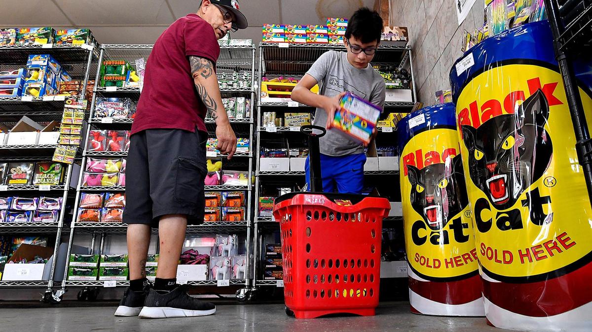Anthony Lopez, left, and his son, Mark, 11, load up on fireworks for a Fourth of July celebration while shopping Friday at Save-U-More Fireworks in Kansas City, Kansas. Many fireworks stands are running short on inventory this year. Teri Eickhoff, part owner at Save-U-More, said that she had received two offers to buy her entire inventory from other dealers because they had not yet received their orders.