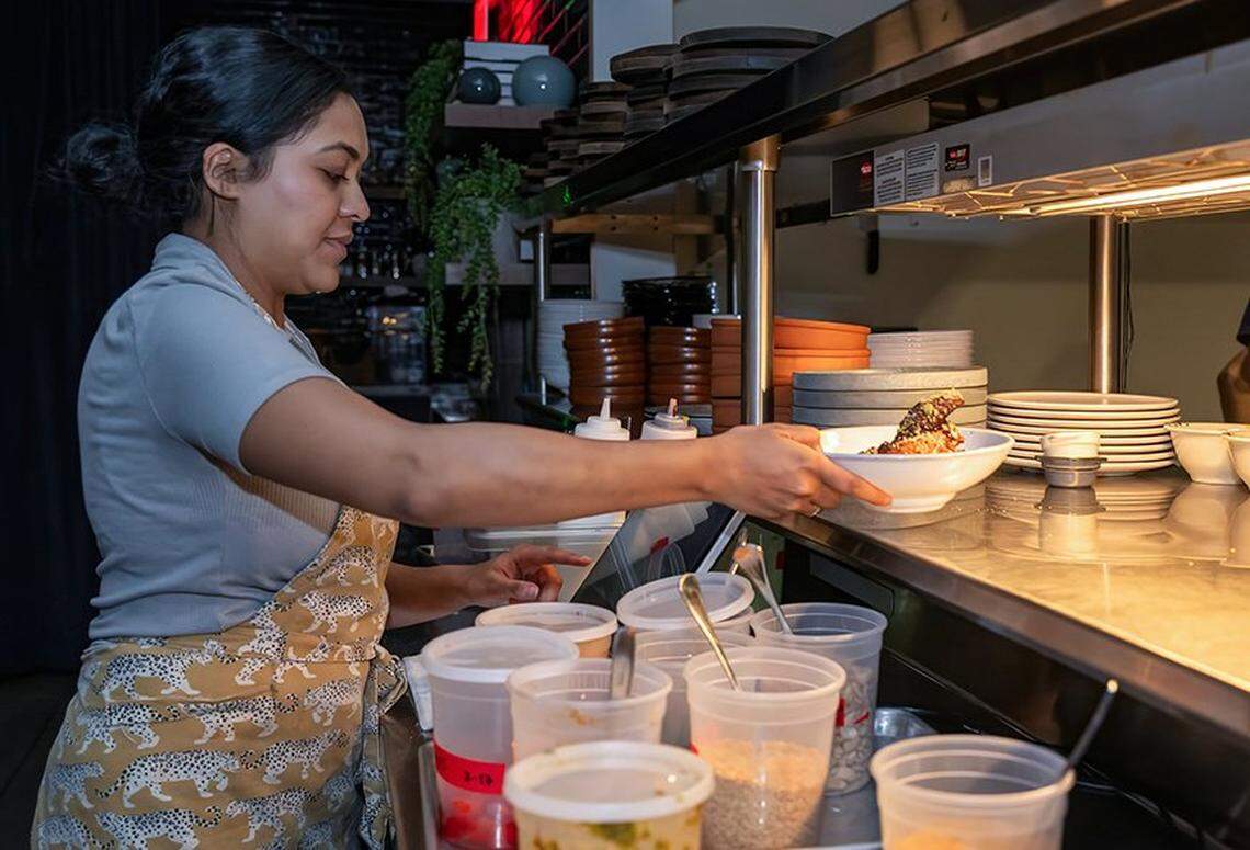 Chef/owner Swetha Newcomb grabs a dish on the line during the dinner rush at Of Course Kitchen & Co., 7753 W 159th St., in Overland Park on Tuesday, Feb. 24, 2026. 