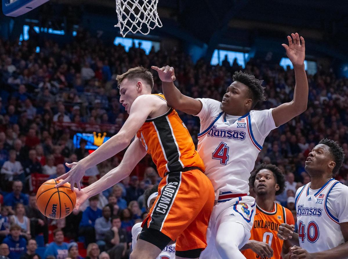 Oklahoma State Cowboys guard Connor Dow (13) and Kansas Jayhawks guard Rakease Passmore (4) go for the ball in the second half at Allen Fieldhouse on Saturday, Feb. 22, 2025, in Lawrence, Kansas.