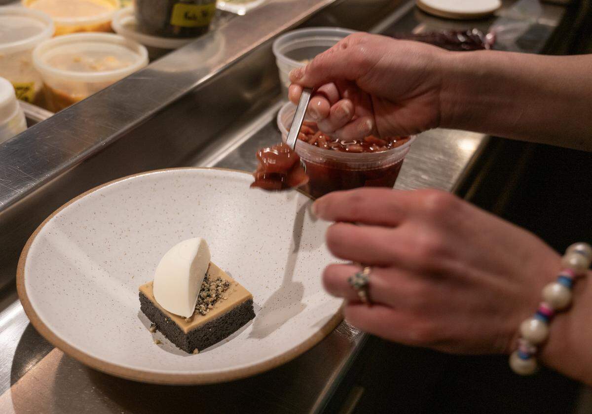 Executive Pastry Chef Helen Jo Leach of The Town Company, who has been nominated for a James Beard award, gently adds red wine poached pears to an order of Black Sesame Almond Cake served with yogurt ice cream. The item is a staple on the menu for the James Beard nominated chef.
