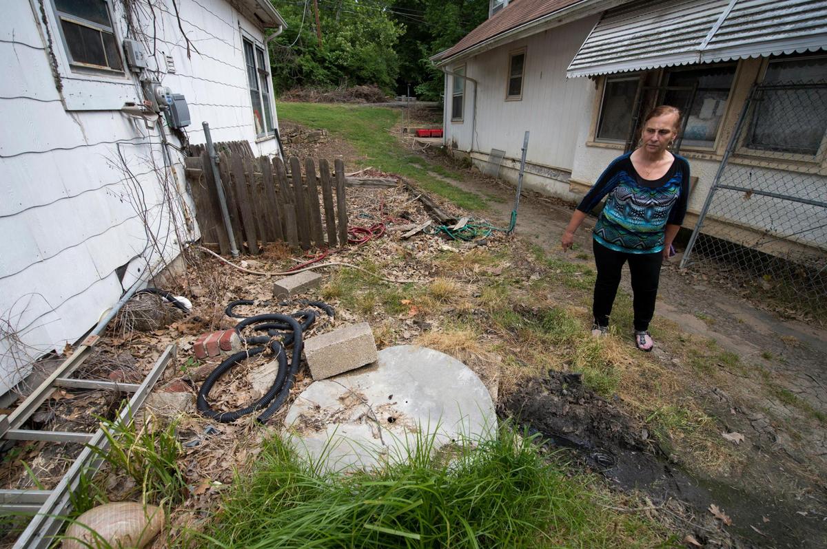 Patricia Losiewicz, a longtime resident of the Swope Ridge neighborhood, looks at a hole in the ground that is her septic system. She says the neighborhood was promised a sewer system years ago.