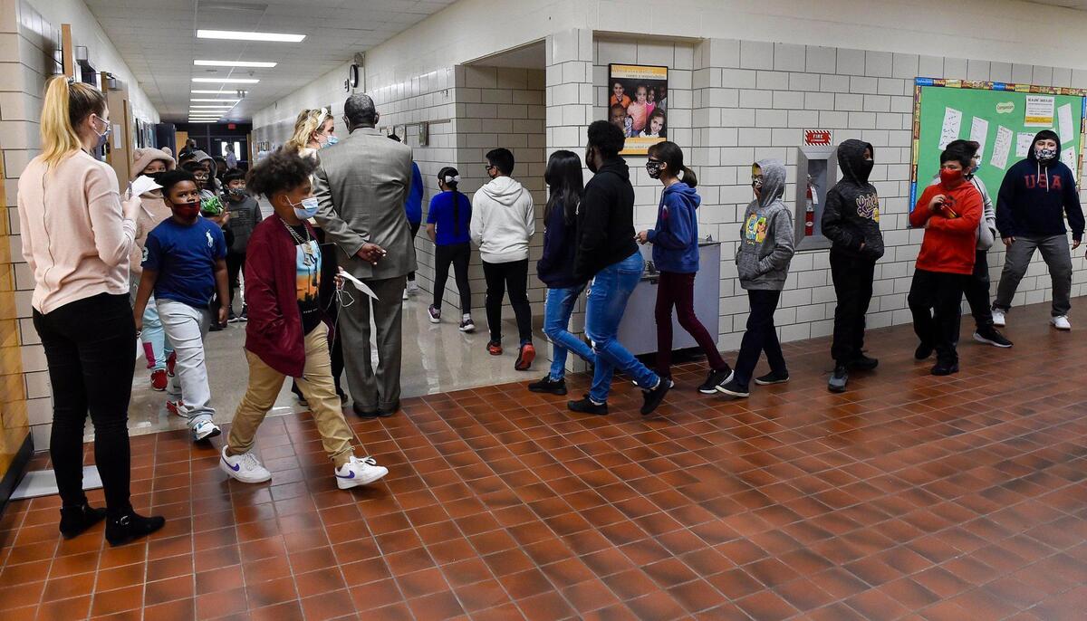 Two classes socially distance as they pass in a hallway. Students arrived at Douglass Elementary School in Kansas City, Kansas, Wednesday, March 31, 2021, for the first day of full in-person learning. According to Principal Louis Neal, about 75 percent of students are coming back for in-person learning.