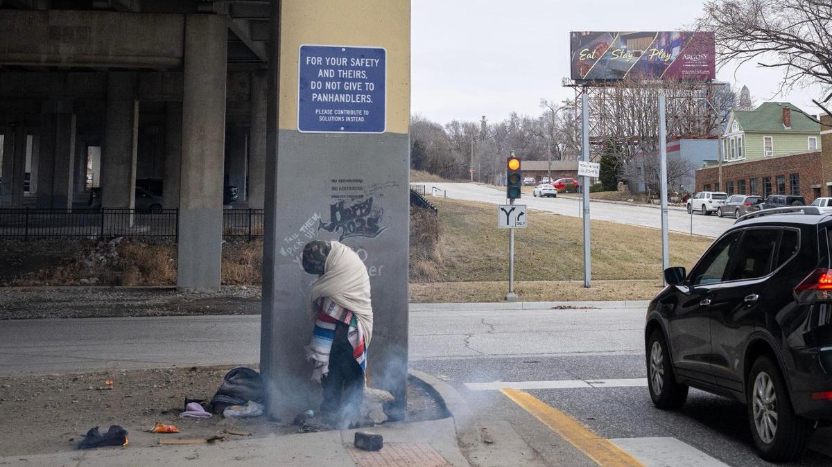 Thomas Gonzales, 38, and homeless for three years, huddles against the cold and beneath a sign, its author unknown, advising people not to give to panhandlers. The sign was put up at the I-35 underpass at West Pennway Street. 