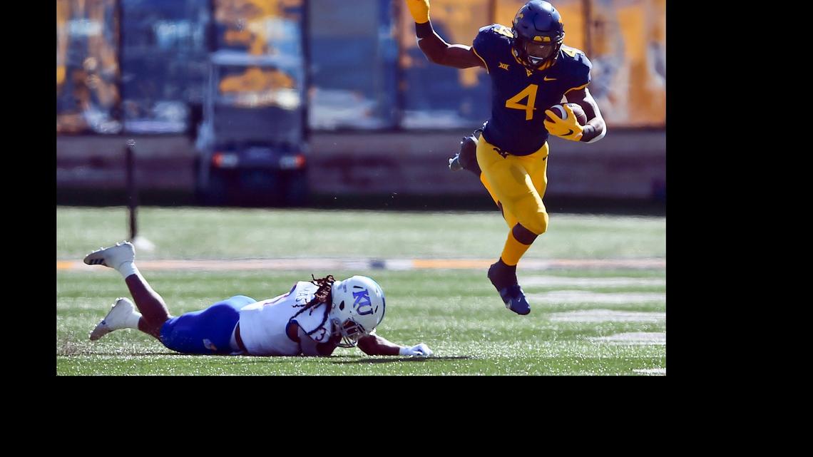 West Virginia running back Leddie Brown (4) slips a tackle by Kansas safety Ricky Thomas (3) during an NCAA college football game Saturday, Oct. 17, 2020, in Morgantown, W.Va. (William Wotring/The Dominion-Post via AP)