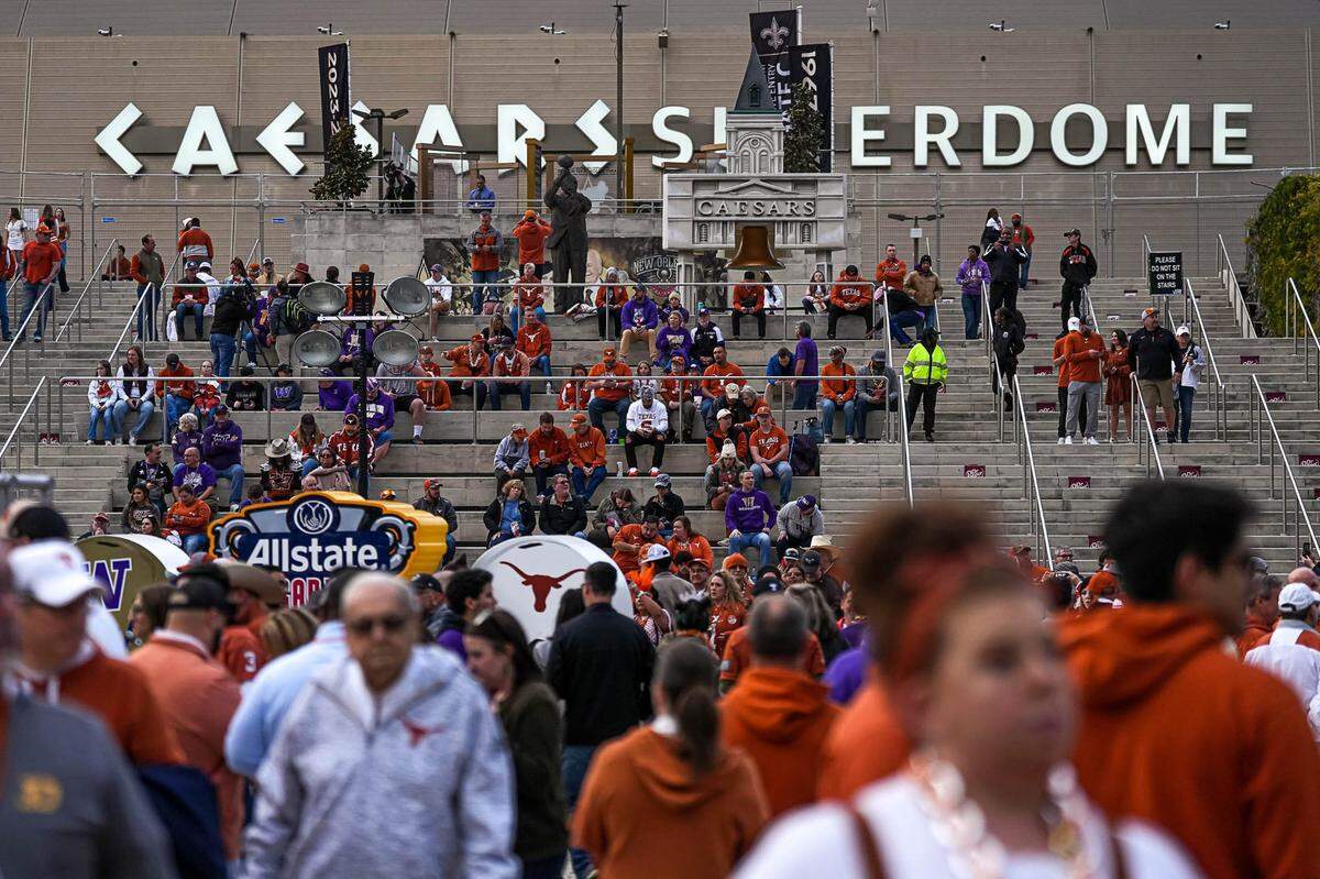 College football fans sit at the front steps of the Superdome in New Orleans ahead of a College Football Playoffs game in January 2024. Now, NFL fans will descend on the city for Super Bowl LIX.