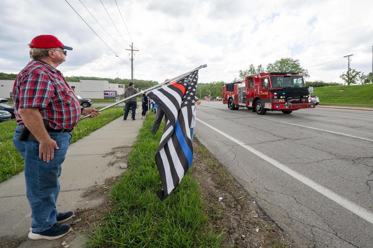 A firetruck carrying the body of fallen KCFD firefighter Grant Hoffman passes bystanders on Bannister Road in Kansas City on Friday, May 2, 2025.
