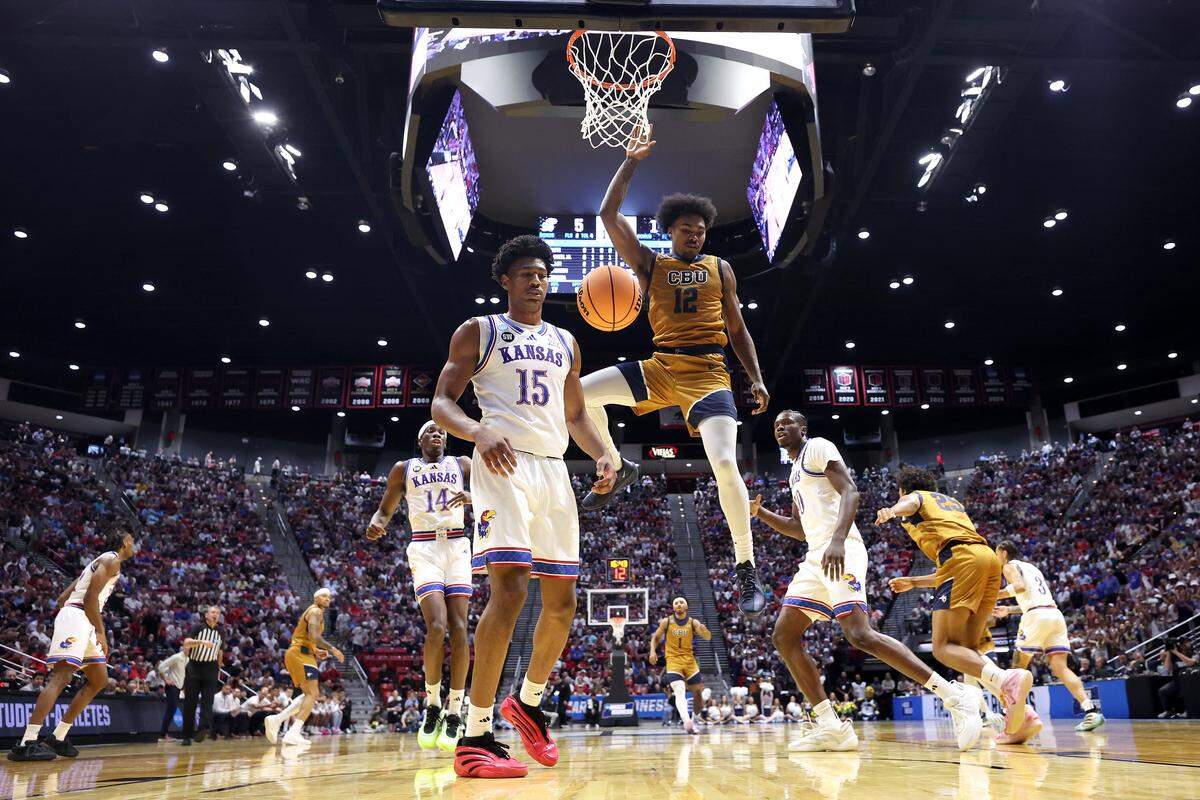 Devon Malcolm #12 of Cal Baptist dunks the ball over Bryson Tiller #15 of Kansas during the 2026 NCAA Tournament at Viejas Arena in San Diego.