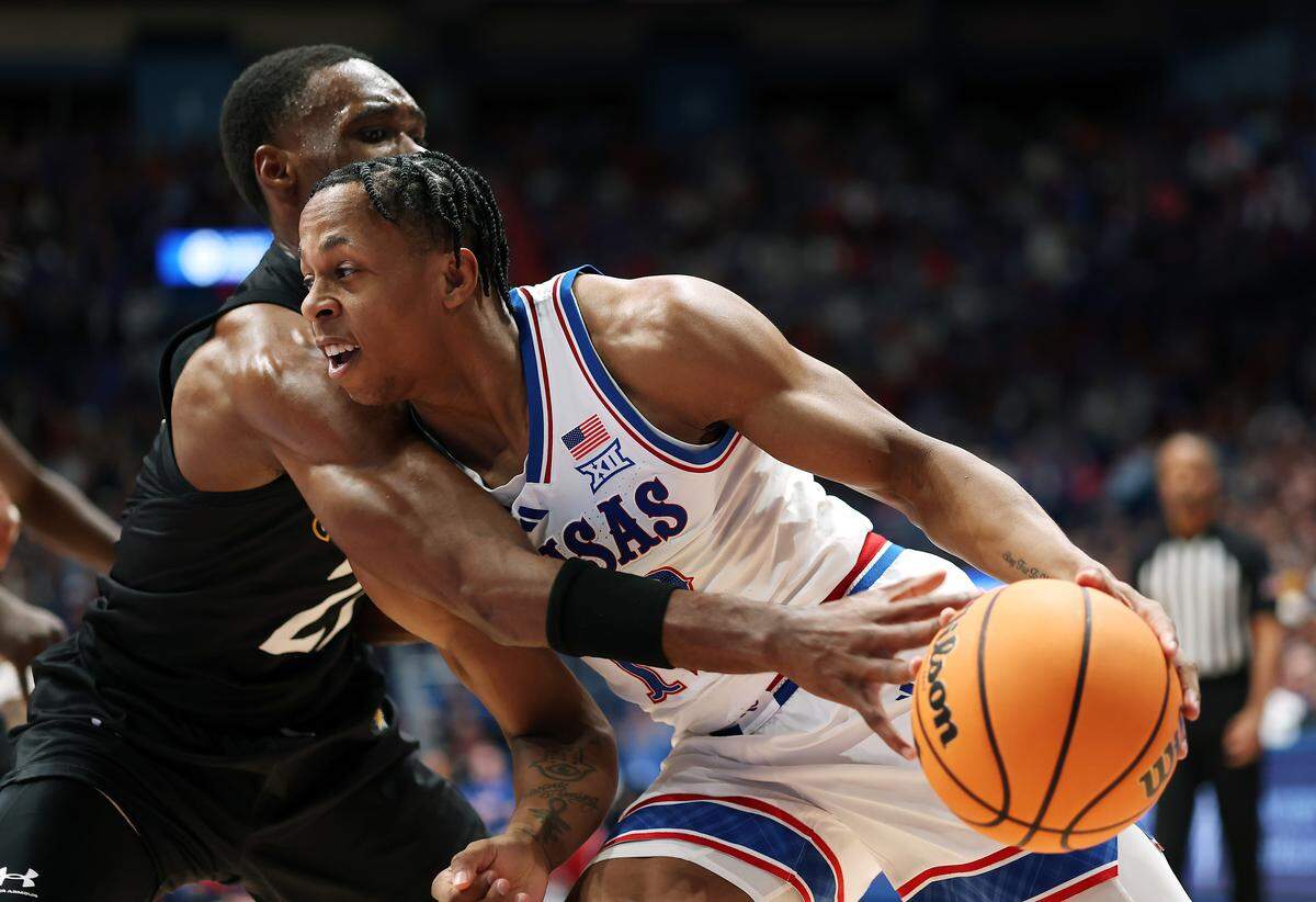 Elmarko Jackson #13 of the Kansas Jayhawks drives to the basket as Jack Doumbia Jr. #21 of the Towson Tigers defends during the game at Allen Fieldhouse on December 16, 2025 in Lawrence.