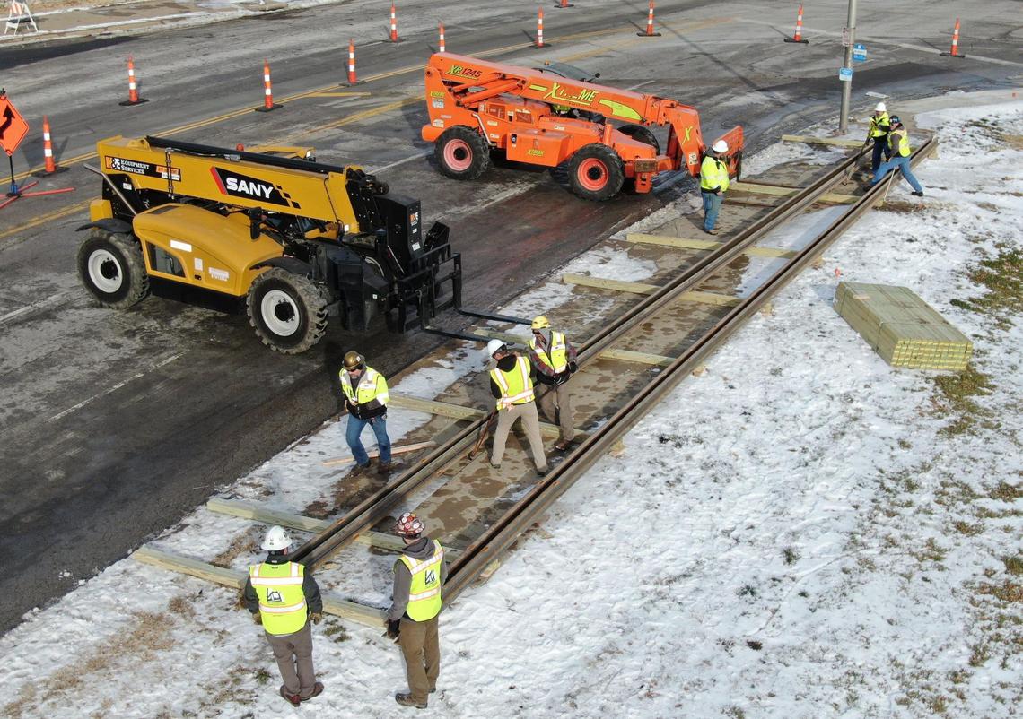 The first delivery of rails for the KC Streetcar Main Street Extension were delivered to the construction site at 27th and Main streets where workers guided the rails onto wood beams as they were unloaded on Tuesday, Jan. 4, 2022, in Kansas City. Over a four-week period, 458 sticks of rails, each 80 feet long and weighing 3,100 pounds, will be delivered for the construction of the streetcar extension which will take about two-and-a-half years.