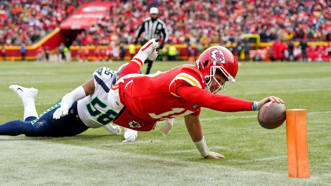 Kansas City Chiefs quarterback Patrick Mahomes (15) dives for a touchdown against Seattle Seahawks linebacker Jordyn Brooks (56) during a 2022 game at GEHA Field at Arrowhead Stadium.