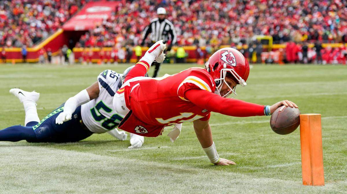 Kansas City Chiefs quarterback Patrick Mahomes (15) dives for a touchdown against Seattle Seahawks linebacker Jordyn Brooks (56) during a 2022 game at GEHA Field at Arrowhead Stadium.