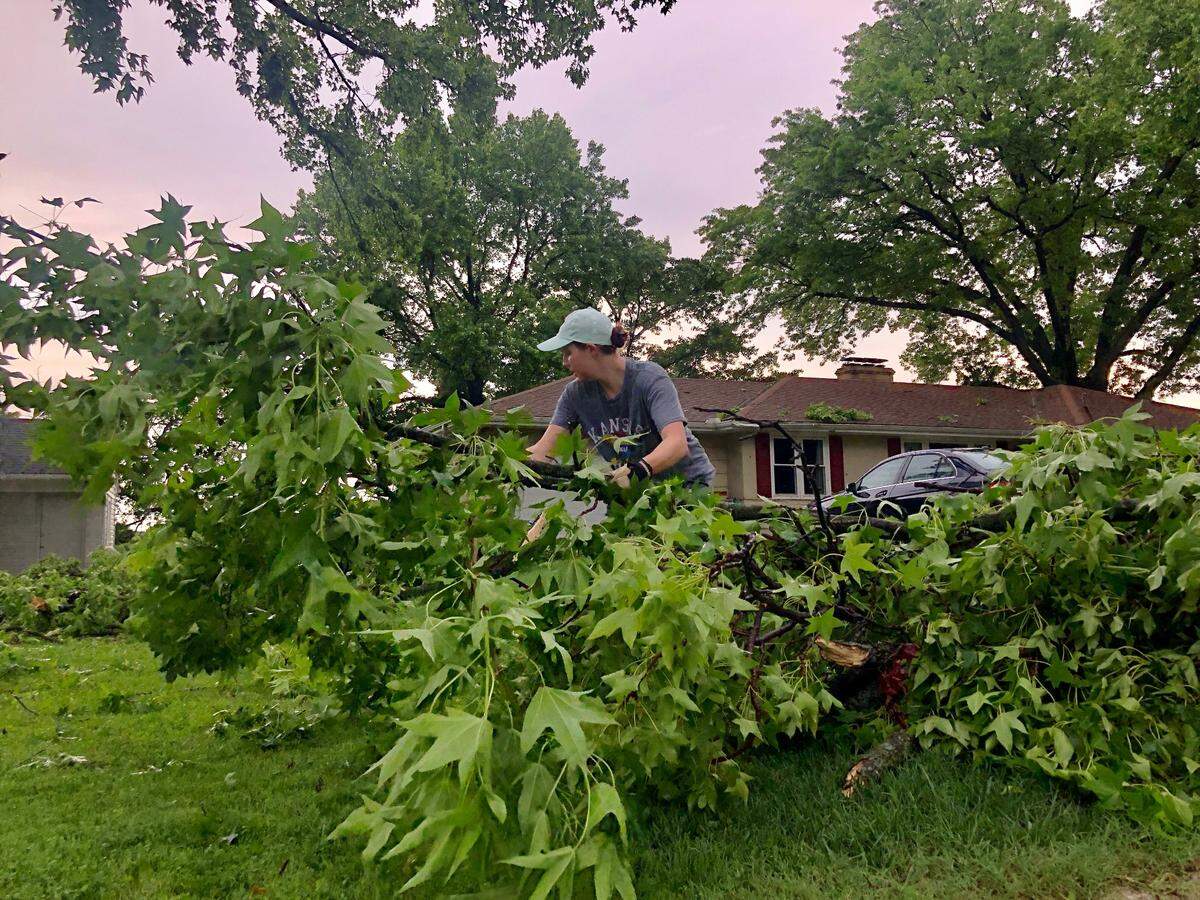 Ty Vaughn, 28, cleaned up downed limbs in her Kansas City yard on West 96th Street, off Wornall Road, on Wednesday, June 8, 2022, following a tornado warning that caused damage across the metro.
