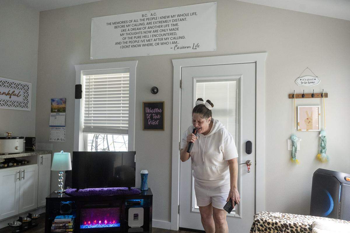 Cariann Lile, 56, sings Tracy Chapman's “Give Me One Reason” inside her tiny home at Eden Village on Tuesday, May 12, 2026, in Kansas City, Kansas. Lile, an aspiring singer who experienced homelessness for six years before moving into the community in September 2024, says the stability of her soundproof home, where she often performs karaoke, feels like "winning the lottery."