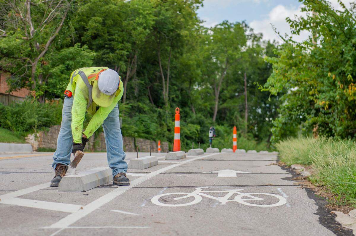 Crew members from Parrish and Sons Construction install parking blocks for the new bike lanes along Hickman Mills Drive in Kansas City on Aug. 5.