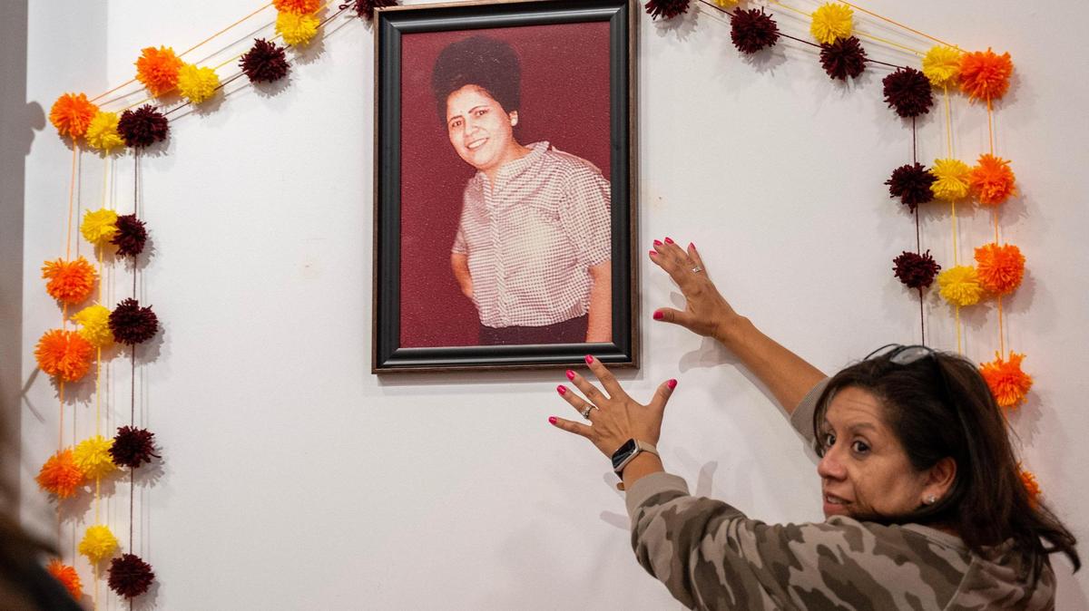 Liz Freeman places her mother’s framed photograph near her family’s alter at the Dia de los Muertos exhibit at the Mattie Rhodes Center.